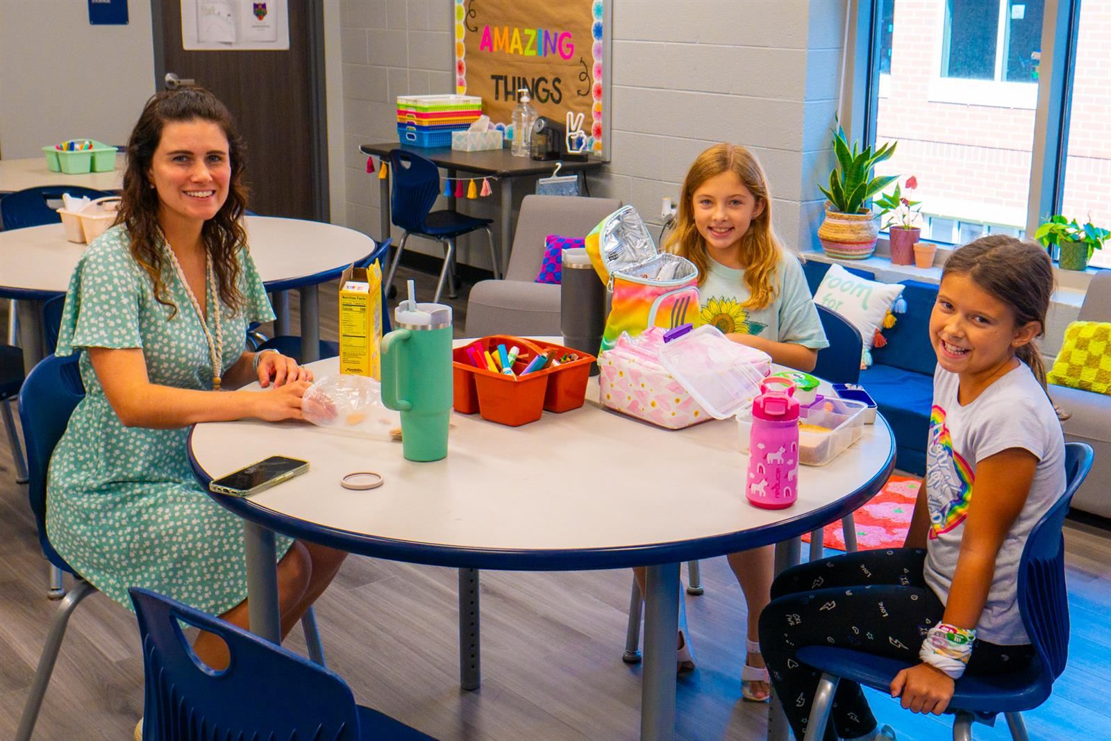 teacher and students sitting at a table eating lunch